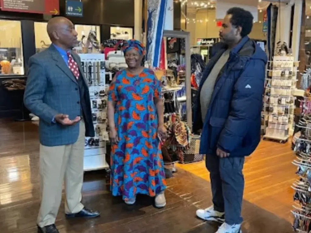 Store community moment — Aimee with visitors, full product display, vibrant signage, authentic energy